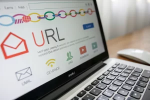 A vibrant digital screen depicting a URL shortener interface. The interface shows a process of creating a branded link, surrounded by email icons. The image captures a clean workspace with vivid lighting and environmental elements like a keyboard and mouse, emphasizing a modern digital atmosphere.