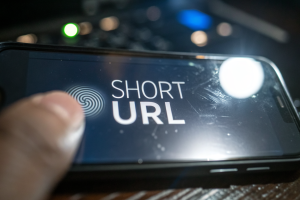 Extreme close-up of a smartphone screen showing a custom-branded short URL and a call-to-action button with a finger hovering above, featuring blurred background and reflections.